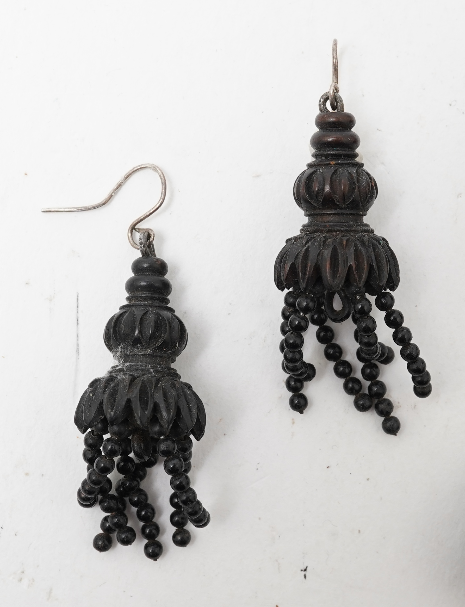 A collection of jewels, comprising: a moulded bog oak brooch depicting a hand holding a posy, length 7.4cm; a carved jet brooch depicting a Gothic ruin, possibly part of Whitby Abbey; a necklace composed of polished pane